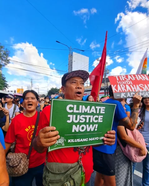 Mielenosoittaja vaatii ilmasto-oikeudenmukaisuutta Filippiineillä. Vihreässä kyltissä lukee: "Climate justice now!"