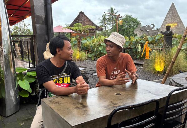 Kaksi indonesialaista nuorta miestä istuu pöydän ääressä juttelemassa