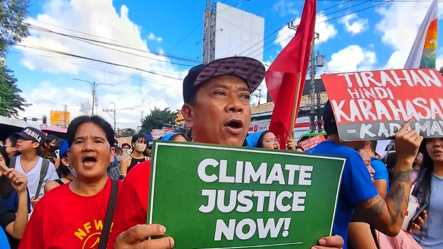 Mielenosoittaja vaatii ilmasto-oikeudenmukaisuutta Filippiineillä. Vihreässä kyltissä lukee: "Climate justice now!"